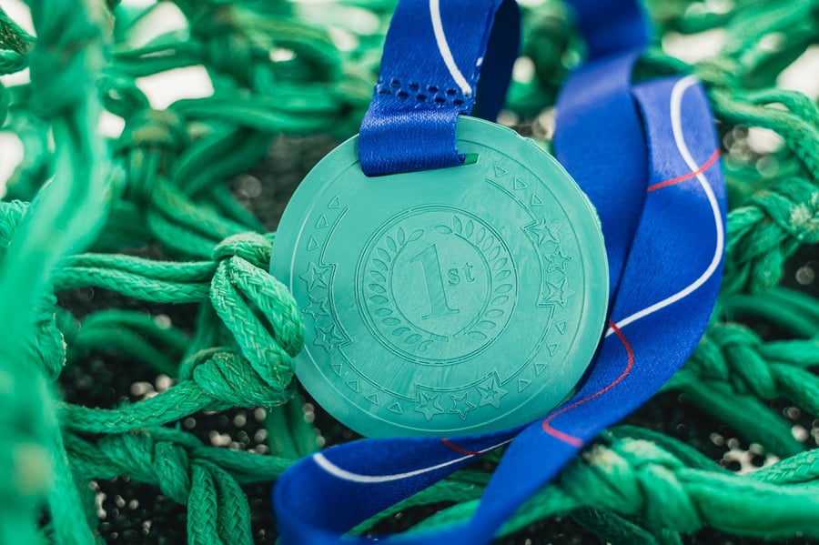 A medal made of fishing nets, sitting among fishing nets.