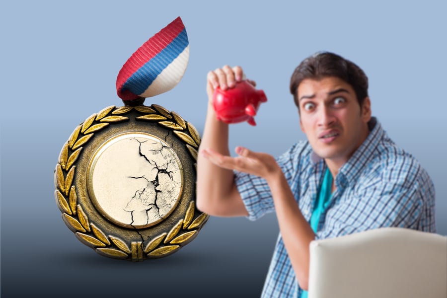 Man with empty piggy bank stands in front of cheap medal.