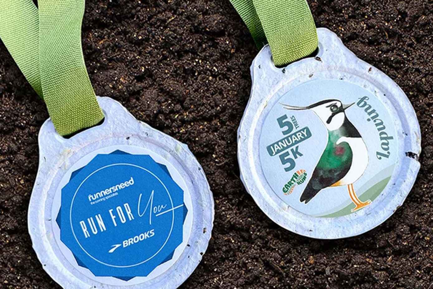 Biodegradable flower seed and newspaper medals being planted in soil.